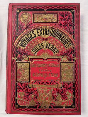 a red book with gold lettering on it sitting on a white surface