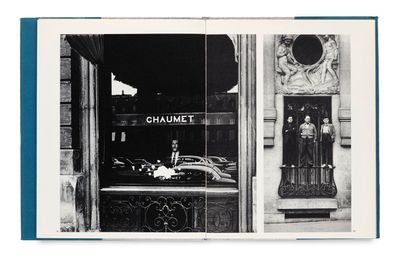 photo en noir et blanc d'un livre ouvert sur une page où figure l'image d'une devanture de magasin