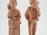 paire de figurines sculptées représentant un garçon et une fille tenant un bébé dans leurs bras