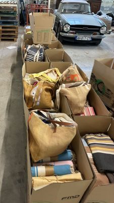 de nombreux cartons remplis d'objets dans un garage, avec une voiture en arrière-plan