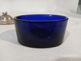 un saladier en verre bleu posé sur une table blanche
