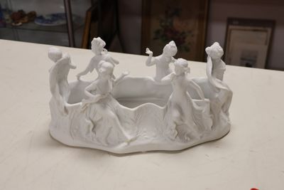 a small white bowl with figurines on it