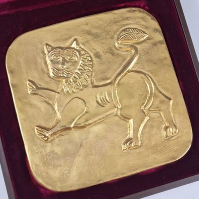 une assiette en or ornée d'un chat, dans une boîte rouge