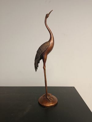 statue of a crane on a stand on a black table