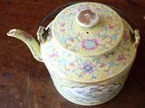 a yellow tea pot with a handle on a table