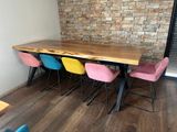 brightly colored chairs sit at a wooden table in front of a brick wall
