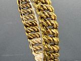 an image of a gold bracelet on display on a clear surface