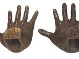 pair of bronze hands with holes in them on a white background