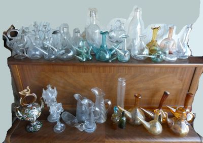 many glass vases on a wooden shelf in a room