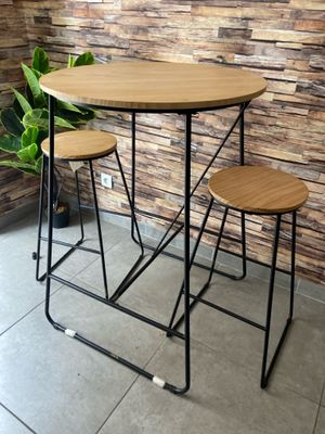 three stools and a table in front of a brick wall
