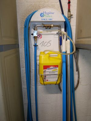 un tuyau bleu fixé au mur, auquel est raccordé un récipient jaune