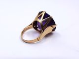 an image of a gold ring with a purple stone in it
