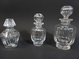 three clear glass perfume bottles sitting on top of a black surface