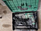 une boîte à outils verte posée par terre, contenant des outils