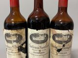 trois bouteilles de vin posées sur une table l'une à côté de l'autre