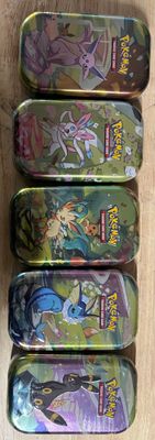 Six boîtes Pokémon sont alignées sur une surface en bois