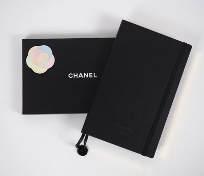 un cahier noir sur lequel est collé un autocollant, à côté d'une boîte noire