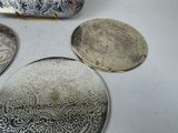 four silver plates and a purse sitting on a table