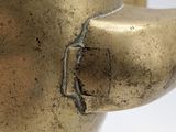 a close up of a brass teapot on a white surface