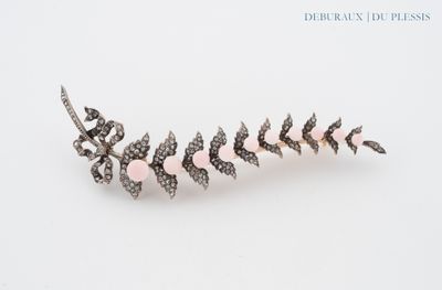 a close up of a brooch with pink stones on a white surface
