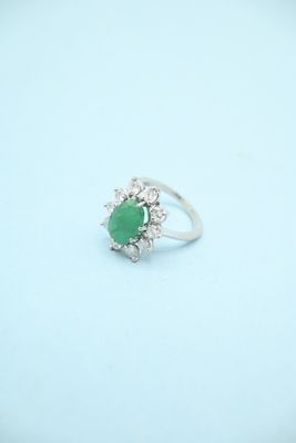 an image of a ring with a green stone surrounded by white diamonds