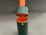a green and orange cup with a handle in the shape of an umbrella