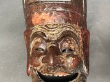 a wooden mask with a smile on it ' s face