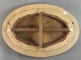 an oval wooden plaque with a cross on it on a gray surface
