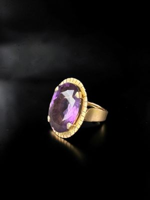 a close up of a gold ring with a purple stone