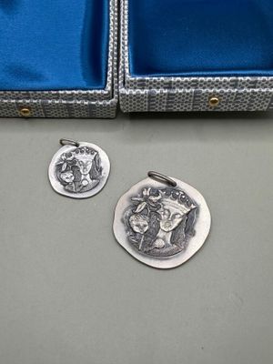 deux pièces d'argent dans un étui bleu posé sur une table, à côté d'une pièce d'argent