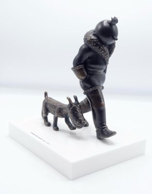 figurine représentant un homme avec un chien, sur un socle blanc