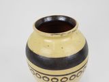 a yellow and black vase on a white surface