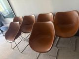 six brown leather chairs are lined up against a wall