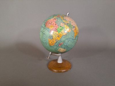 un petit globe vert et jaune posé sur un socle en bois