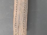 sculpture en bois représentant un homme tenant un couteau, sur un mur gris