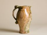un vase marron et vert posé sur une surface blanche