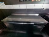 a stainless steel counter in a kitchen with a sign on the wall
