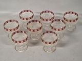 six glasses with red and white designs on them sitting on a white surface
