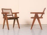 two wooden chairs sitting next to each other in front of a wall