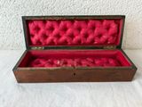 a small wooden box with red fabric inside of it