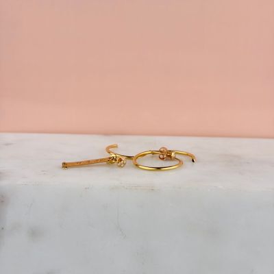 a close up of a pair of gold hoop earrings on a marble surface