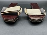 pair of women ' s brown and beige sandals on a black surface
