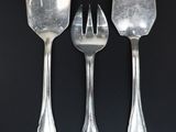 three forks and spoons on a black surface with a black background