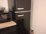 a black refrigerator in the corner of a kitchen