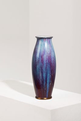 un vase violet et bleu posé sur un socle blanc dans une pièce blanche