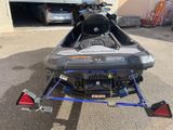 a snowmobile parked in front of a garage with a truck in the background