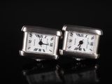 pair of silver cuff watches with roman numerals on a black surface