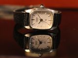 a silver watch sitting on a table next to a red purse