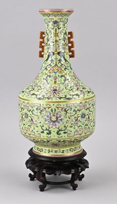 une photo d'un vase vert posé sur un socle en bois