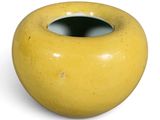 a yellow vase that is sitting on a white surface